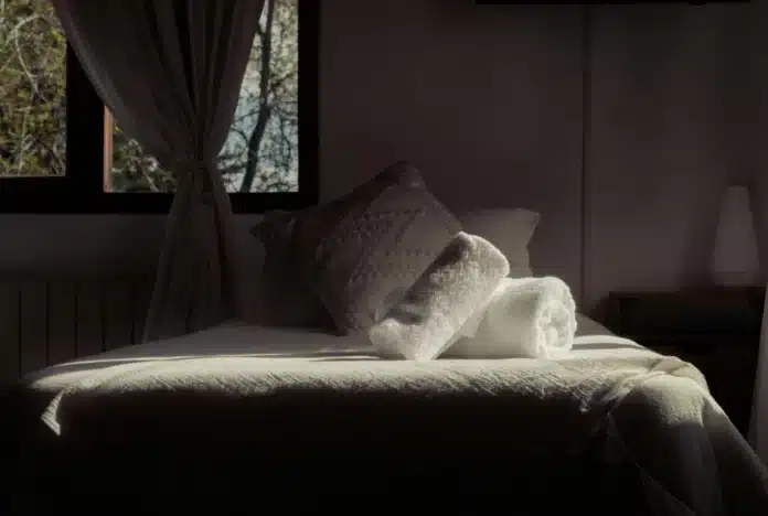 Beli uredan krevet osvetljen prirodnim svetlom