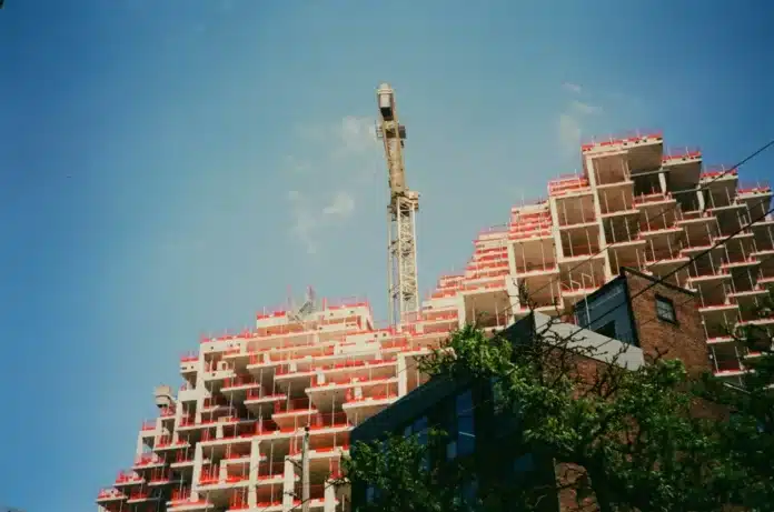 kran pored višespratnice i drveće u urbanom ambijentu