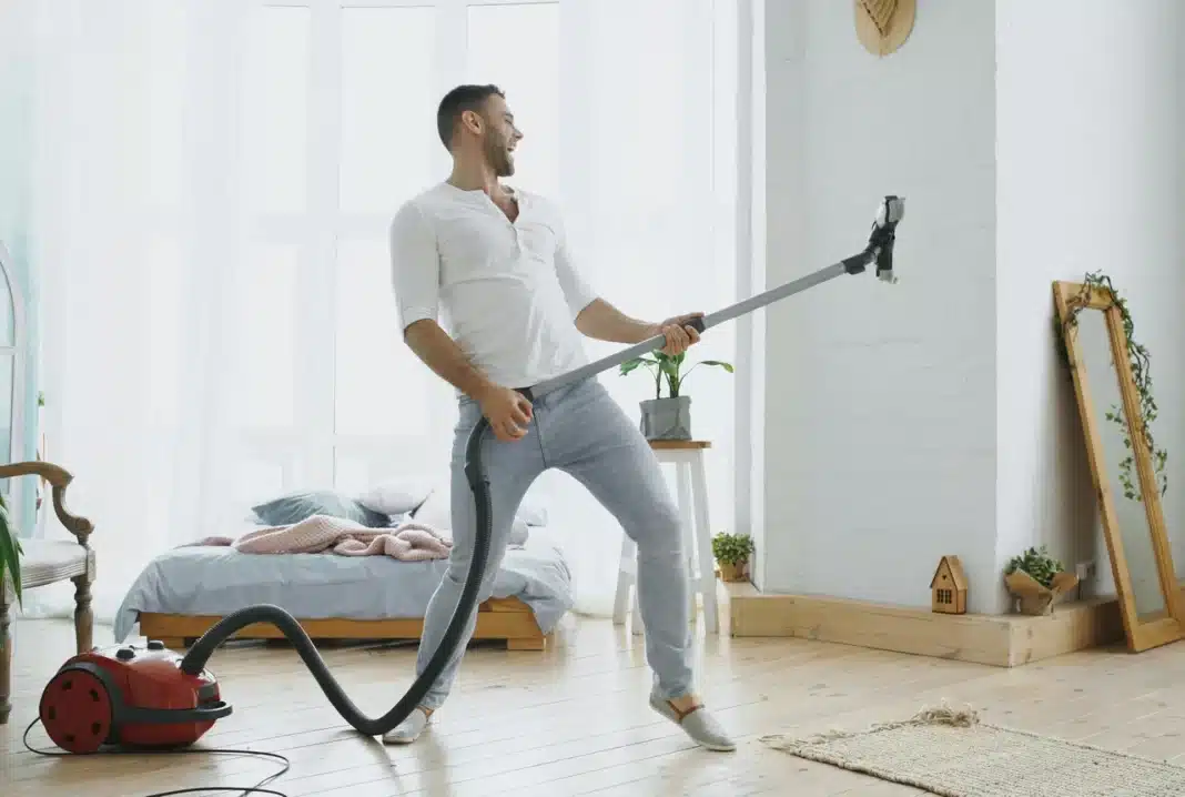 Muškarac usisava sa crevom, prirodna svetlost kroz prozore